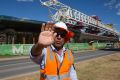 A security guard attempts to stop photographs of the buckled span on the Skytrain viaduct in Sydney's north-west.