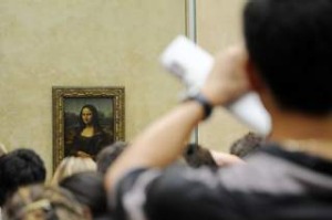 A tourist takes souvenir photos of Italian painter Leonardo da Vinci s famed portrait Mona Lisa at the Louvre Museum in ...