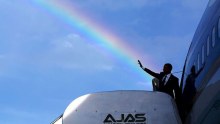 President Barack Obama waves from Air Force One with a rainbow behind him