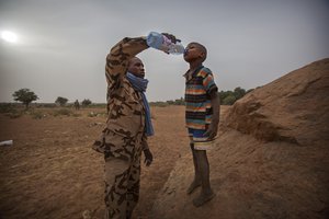 File - A member of the Chadian contingent of the United Nations Multidimensional Integrated Stabilization Mission in Mali (MINUSMA) offers a boy a drink of water, 17 December 2016.