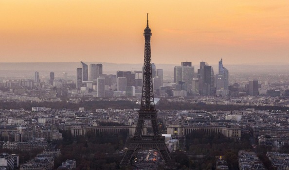 The Eiffel Tower stands above the city skyline at sunset.