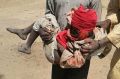 A man carries an injured child following a military air strike at a camp for displaced people in Rann, Nigeria.