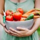 Close-up of a woman holding a bowl of freshly harvested vegetables