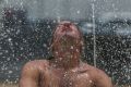 Craig Davis takes advantage of the new sprinkler fountain in Queanbeyan to cool off during the Summer hot spell.