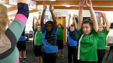 Students in class reaching up into the air.