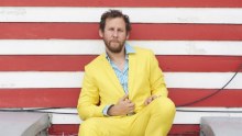 Musician Ben Lee sits in a bright yellow suit.