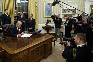 President Donald Trump signs his first executive order in the Oval Office of the White House