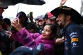 Daniel Ricciardo poses for photographs with fans in pit lane.