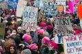 Women with bright pink hats and signs begin to gather early in Washington for the anti-Trump protest.