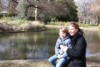 A woman and boy sitting next to a lake in a park.