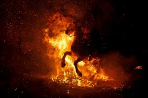 A A woman rides a horse through a bonfire during 'Las Luminarias' Festival.