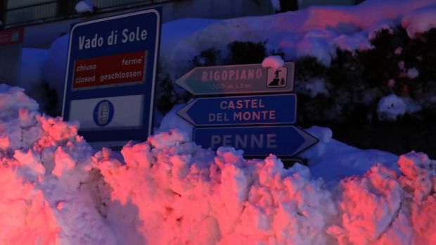 Ploughed snow is piled by road signs indicating nearby towns.