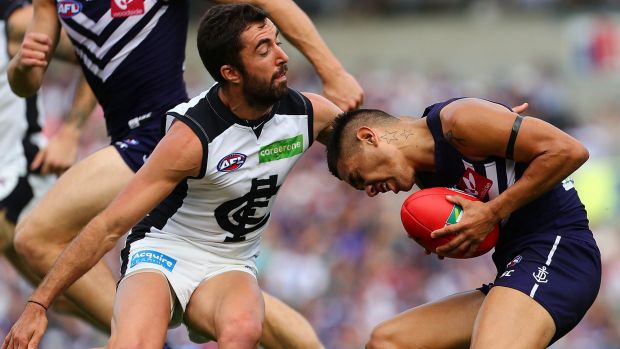 Michael Walters of the Dockers ducks into a tackle by Kade Simpson of the Blues.