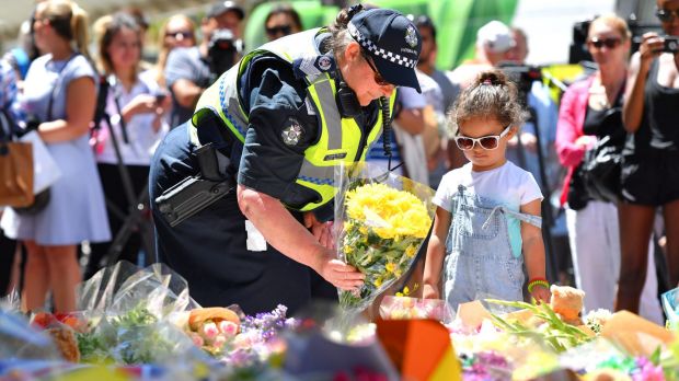 A policewoman and a young girl contribute to floral tributes outside the old Melbourne GPO.