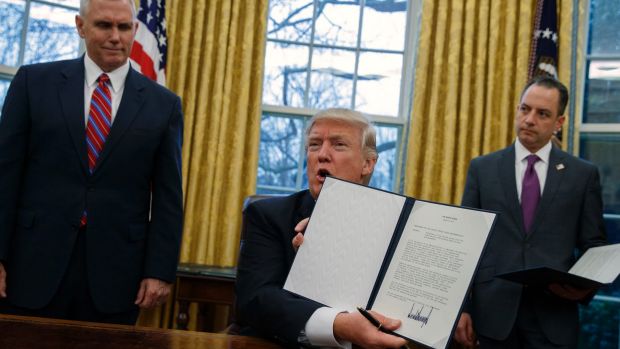 President Donald Trump (centre) shows off an executive order.