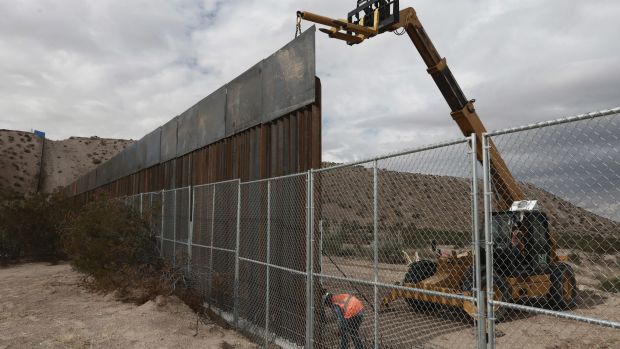 Workers raise a taller fence along the Mexico-US border between the towns of Anapra, Mexico and Sunland Park, New Mexico.