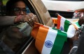 An Indian commuter buys the Indian flag from a street vendor at a traffic intersection on the eve of India's Republic ...