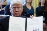 US President Donald Trump displays one of five executive orders he signed related to the oil pipeline industry for a ...