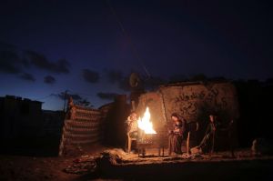 A Palestinian family warm themselves up with a fire outside their makeshift house during a power cut in a poor ...
