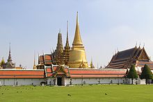 A Thai temple complex with several ornate buildings and a stupa, and a lot of visitors