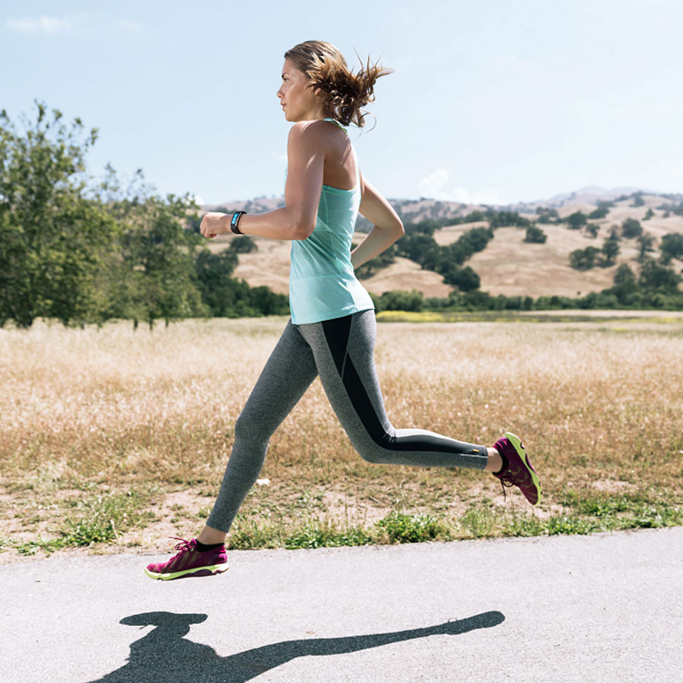 A woman wearing a Microsoft Band jogging on a sunny day.