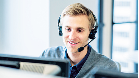 Man wearing headset, responding to a call while looking at his monitor