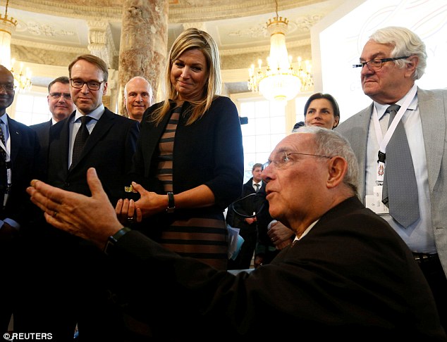 The royal speaks to guests including German Finance Minister Wolfgang Schaeuble (seated) following her opening speech at the conference at Biebrich Palace on Wednesday