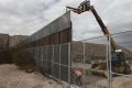 Workers raise a taller fence along the Mexico-US border between the towns of Anapra, Mexico and Sunland Park, New Mexico.