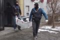 Masked police officers carry computers out of a house in Graz, Austria. 