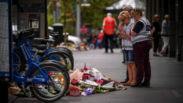 People leave floral tributes along Bourke Street.