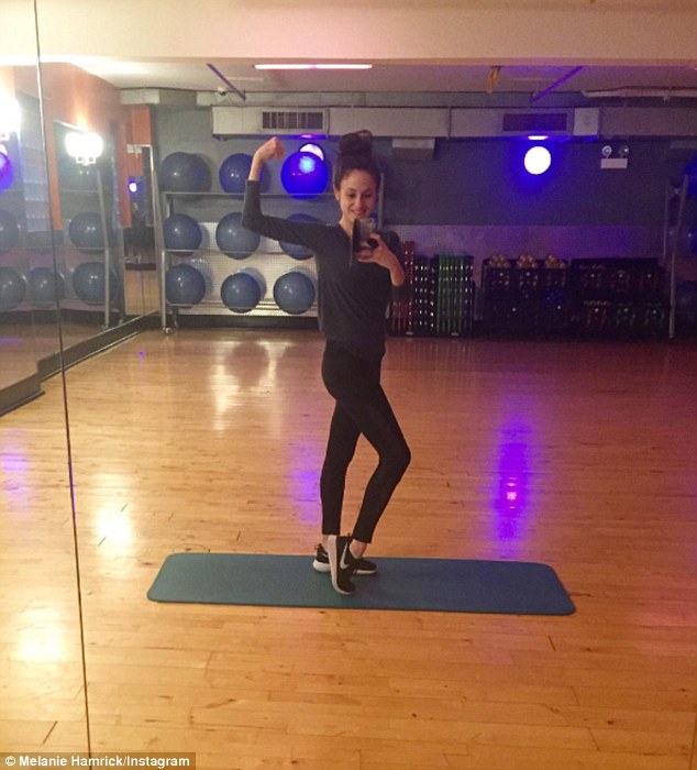 'Gym day for a baby workout!': In another gym snap, she was dressed in black leggings and a sweatshirt which highlighted her slim figure as she flexed her bicep