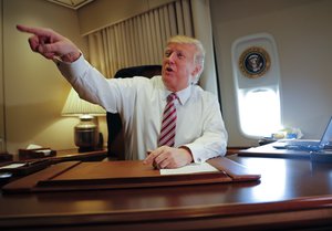 President Donald Trump points towards members of the media while seated at his desk on Air Force One upon his arrival at Andrews Air Force Base, Md., Thursday, Jan. 26, 2017.