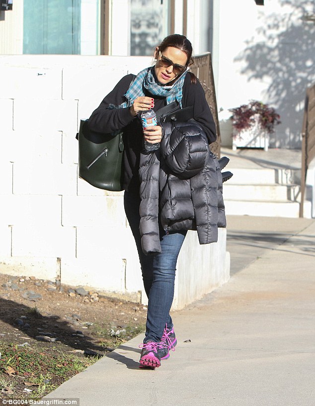 Walking and talking: Jennifer Garner jammed her phone under her ear while opening a bottle of water and carrying a bag and her puffa jacket when she was spotted out in LA on Thursday