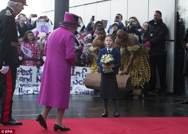 Gift: A schoolgirl waits to give the Queen flowers as two men play an instrument behind