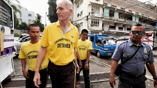 Peter Scully (2nd from left) arrives at the Cagayan De Oro court handcuffed to another inmate on his first day of his ...