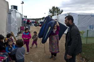 Refugee Zubaida al-Rakad, 35, a Syrian refugee from Deir el-Zour, carries wet mattresses at the refugee camp of Ritsona about 86 kilometers (53 miles) north of Athens, Saturday, Jan. 14, 2017.