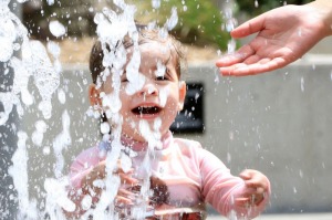 Anika, 2, plays in the water feature in Tumbalong Park, Darling Harbour.