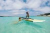 Kuta on top of a paddle board and her owner Erin.