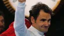 Roger Federer gives a thumbs up in front of a clock