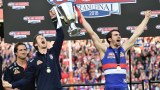 Bulldogs coach Luke Beveridge watches injured captain Robert Murphy (C) lift AFL premiership cup.