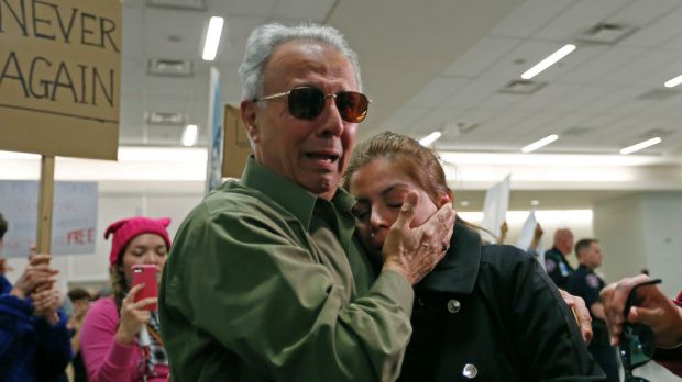 Iranian green card holder Shima Behgooy, right, cries on the shoulders of her father-in-law Ahmad Behgooy, a native of ...