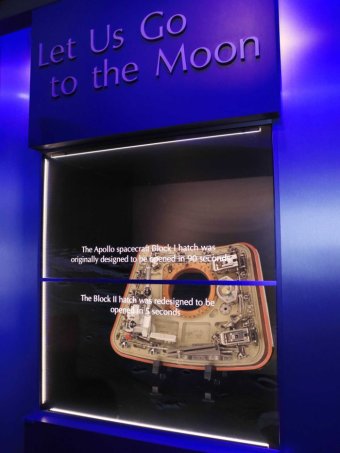 The Apollo 1 capsule hatch is seen in a display cabinet.