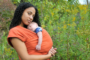 A parent and their newborn in a field of wildflowers.