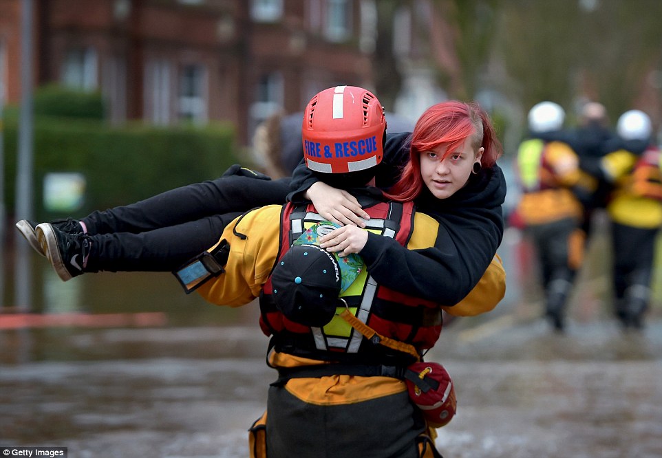 A rescue worker carried a young woman to safety through the flood water as teams continued to evacuate homes in Carlisle (pictured)