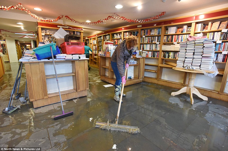Workers at the Book Shop on Main Street in Cockermouth, Cumbria, who were flooded in 2009, start the clean up all over again following the torrential rain over the weekend
