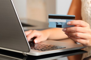 Woman making an online booking with a credit card and a laptop. 