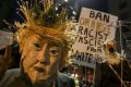 A demonstrator wearing a mask in the likeness of US President Donald Trump protests against his executive order in Los ...