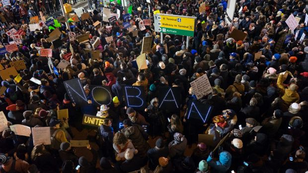 Protesters assemble at John F. Kennedy International Airport in New York after  two Iraqi refugees were detained while ...