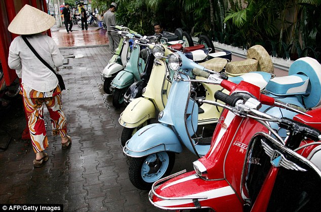 Vespa is better known for its iconic scooters. Here, a woman walks past a row of repaired old scooters displayed for sale along a street in Ho Chi Minh, Vietnam