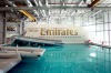 Aircraft emergency escape chutes extend into the training pool, next to an Emirates Airline simulator.